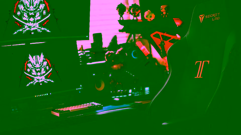 Secretlab gaming chair in a cozy dual-monitor setup with figures and RGB lighting.