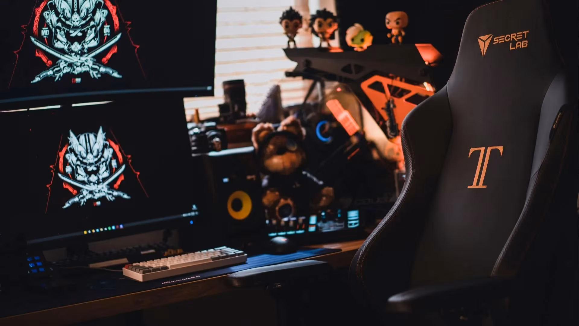 Secretlab gaming chair in a cozy dual-monitor setup with figures and RGB lighting.