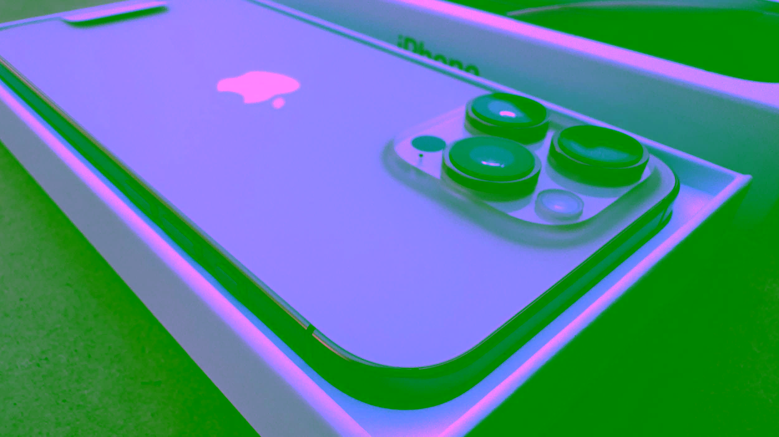 Close-up of the iPhone 16 in its box showing the rear camera lenses, side buttons, and part of the Apple logo.