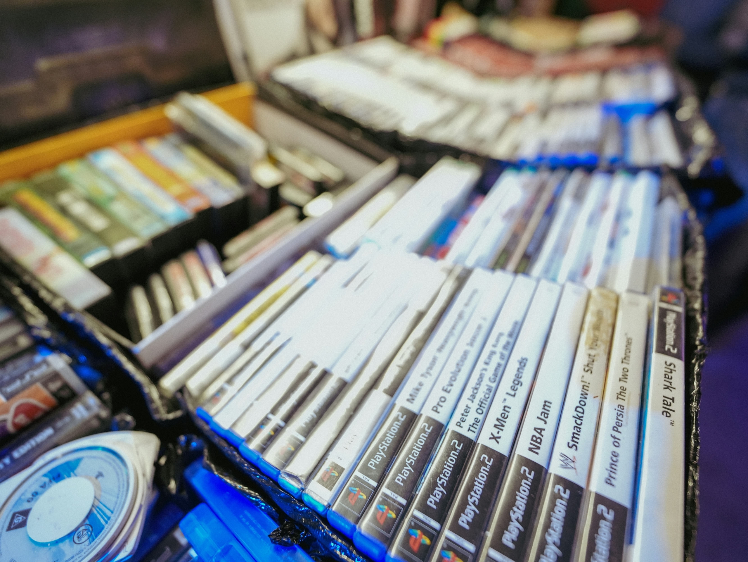 Various video game discs arranged in cases, labeled with titles for PlayStation and Xbox consoles.