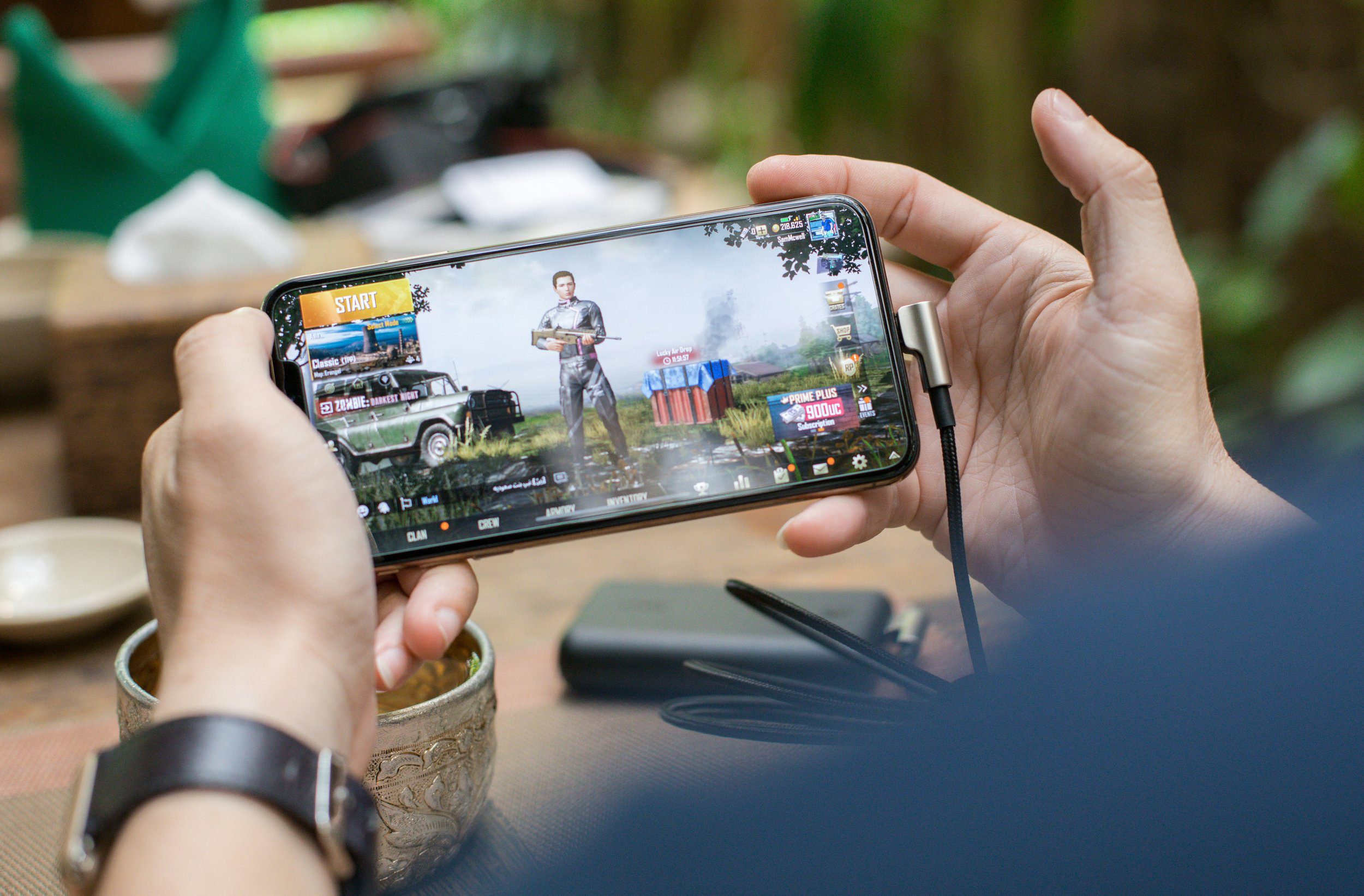 Person playing PUBG Mobile on a smartphone, showing the game's start screen.
